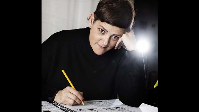 Louise Lindquist Sassene sitter vid bordet och tecknar.