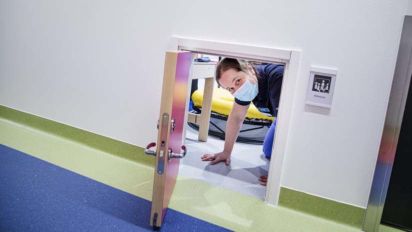 Ellen Odéus tittar fram genom en liten dörröppning