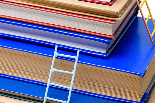 En trave böcker med stegar lutandes mot